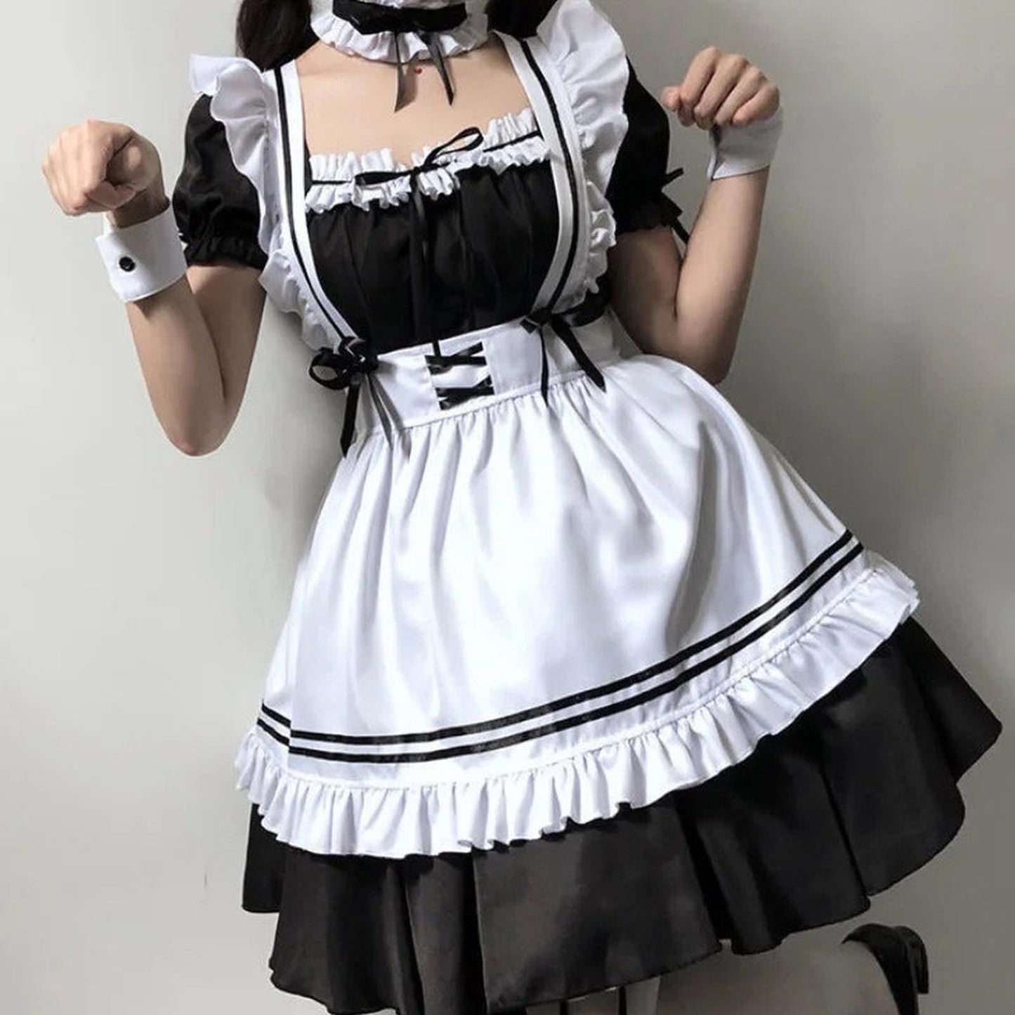 Detalle de blusa negra con volantes blancos y lazos en el delantal de disfraz maid