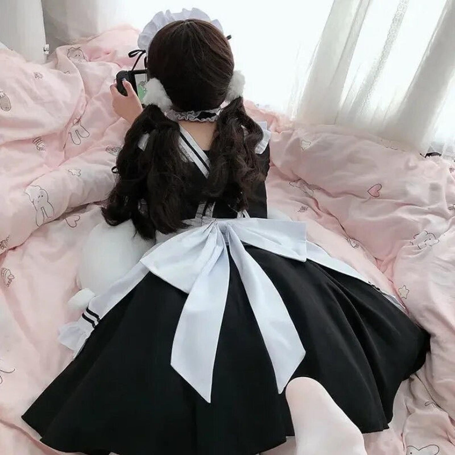 Disfraz maid con orejeras y gran lazo trasero sobre cama decorada para cosplay